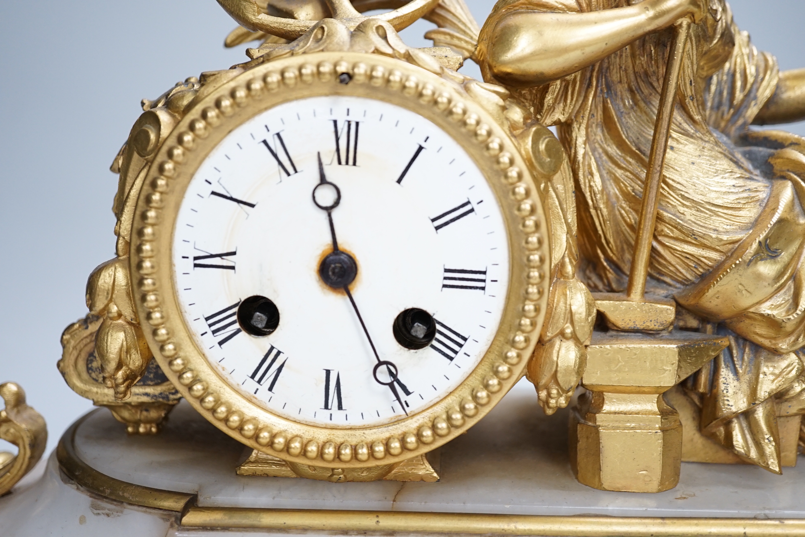 A late 19th century French gilt metal and onyx clock mounted with the figure of Industry holding a locomotive, 42cm wide